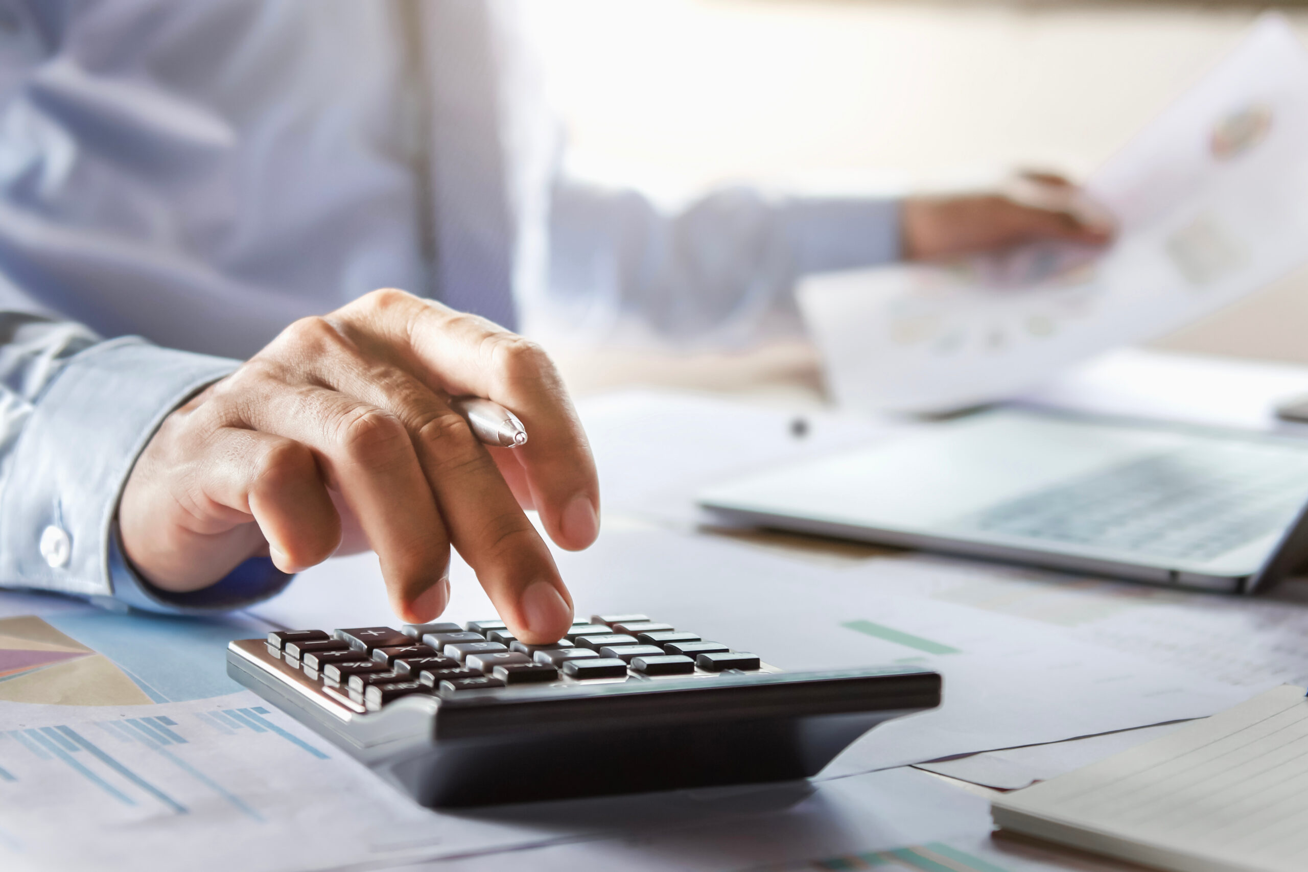 Personne calculant ses impôts et analysant ses documents financiers avec une calculatrice.